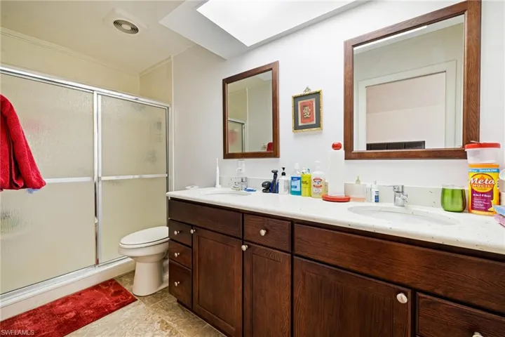 Full bathroom with double vanity, a shower stall, toilet, and tile patterned flooring