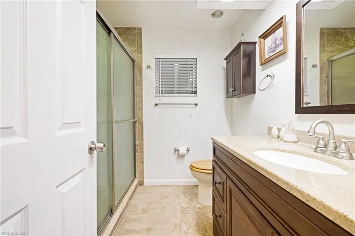 Bathroom featuring vanity, a shower stall, toilet, and baseboards
