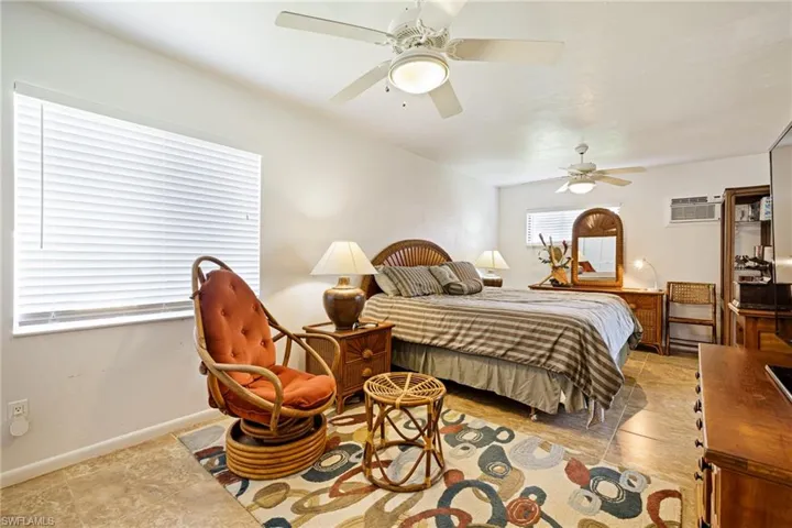 Bedroom featuring a wall mounted AC, ceiling fan, light tile patterned floors, and baseboards