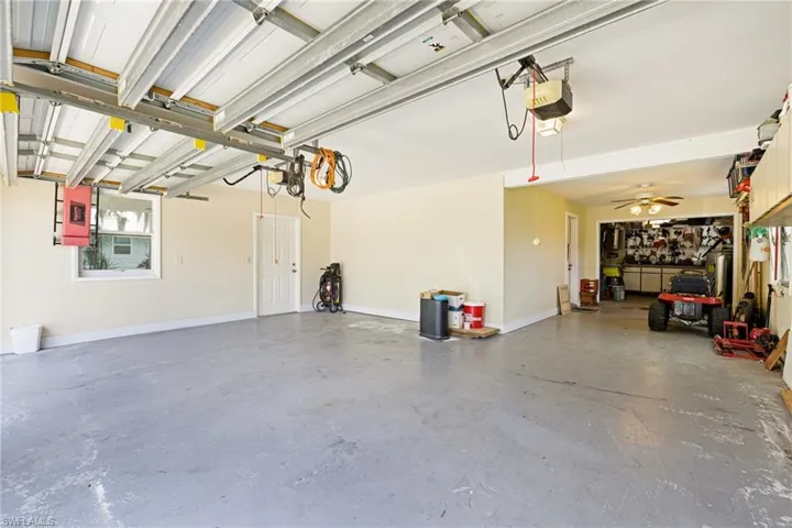 Garage with a garage door opener, baseboards, and a ceiling fan