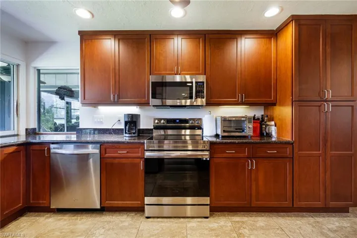 Kitchen with appliances with stainless steel finishes, dark stone countertops, recessed lighting, and a textured ceiling