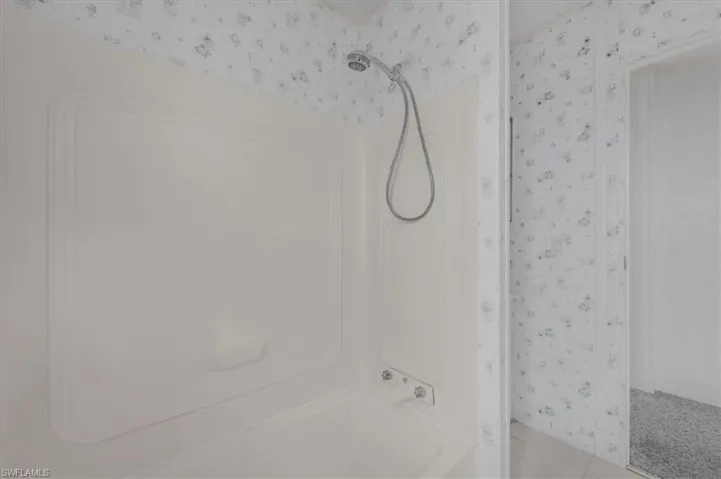 Full bath with wallpapered walls and  shower combination