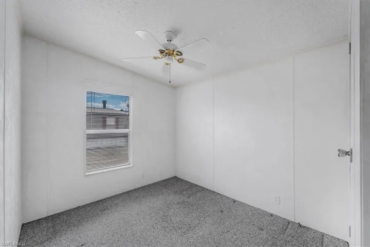 Carpeted spare room featuring ceiling fan and a textured ceiling