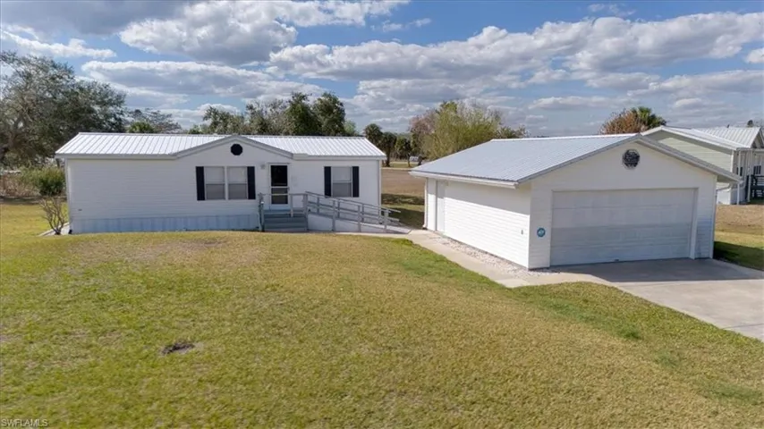 View of front of house featuring an outbuilding, a metal roof, a detached garage, and a front yard