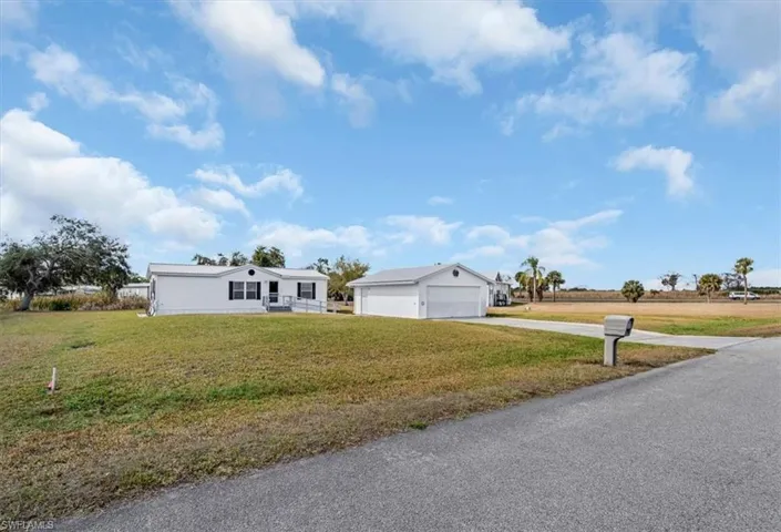 View of front of property featuring a front lawn, a garage, and driveway
