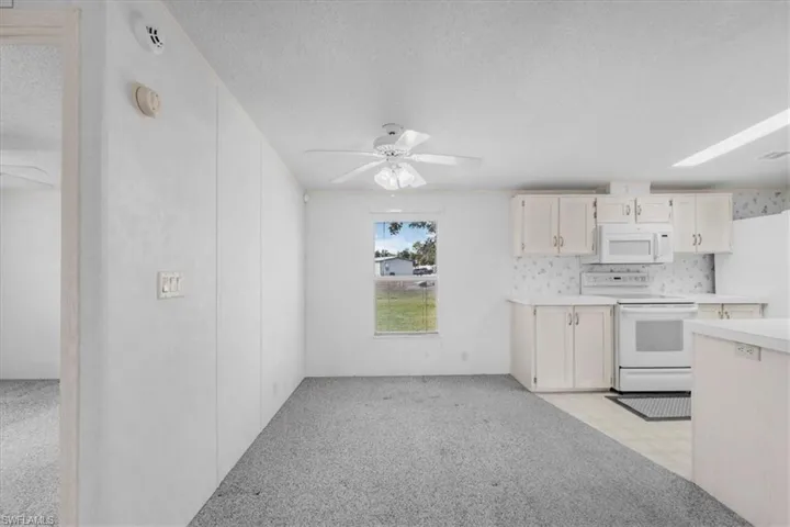 Kitchen featuring a ceiling fan, white appliances, light countertops, a textured ceiling, and light flooring