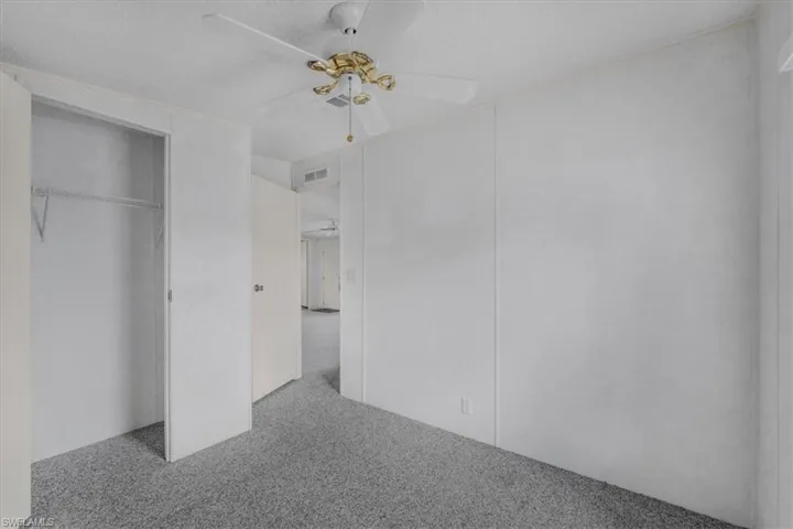 Unfurnished bedroom with light colored carpet, a ceiling fan, a textured ceiling, and a closet