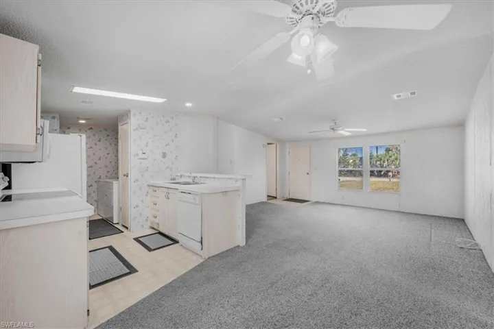 Kitchen featuring light flooring, light countertops, dishwasher, open floor plan, and stove