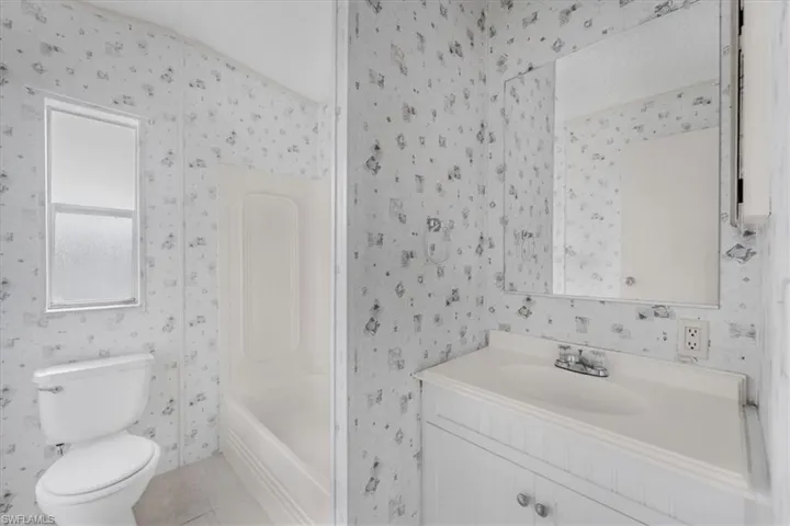 Full bathroom with vanity, light tile patterned floors, and washtub / shower combination