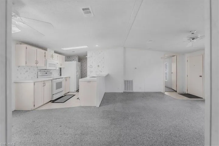Kitchen with ceiling fan, light countertops, white appliances, open floor plan, and a textured ceiling
