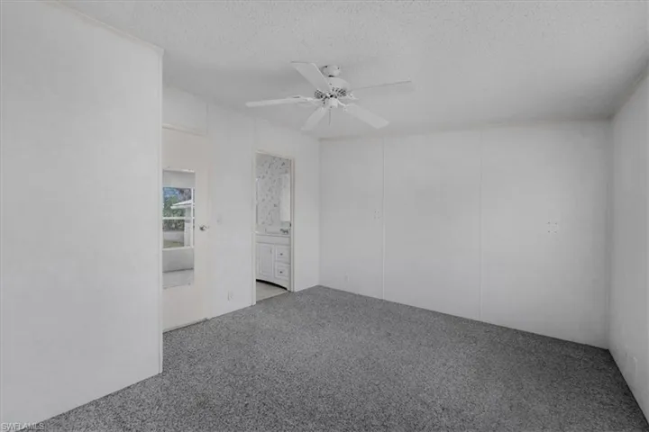 Carpeted empty room featuring a ceiling fan and a textured ceiling