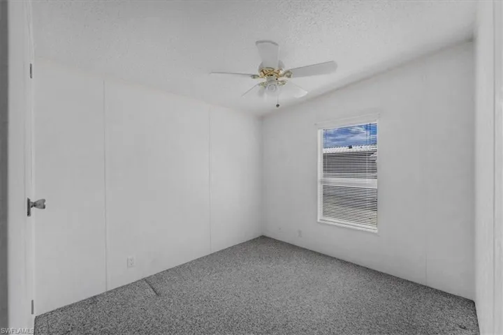 Spare room featuring light colored carpet, ceiling fan, and a textured ceiling