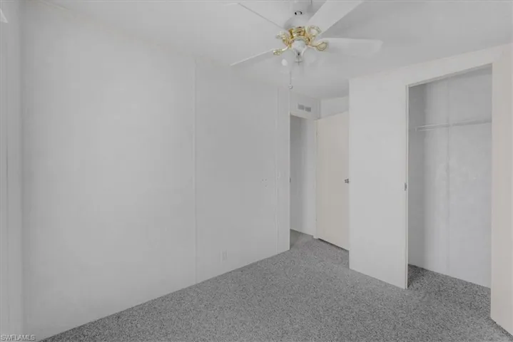 Unfurnished bedroom featuring a ceiling fan, a closet, and light colored carpet