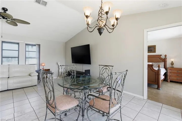 Dining space featuring light tile patterned floors, lofted ceiling, a chandelier, and ceiling fan
