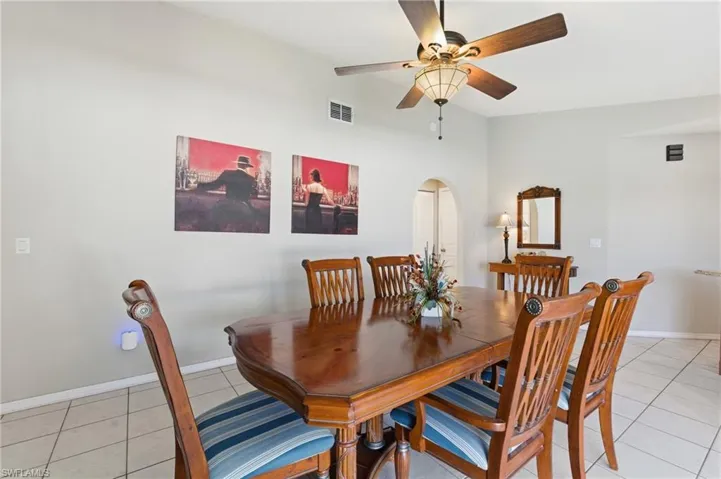 Dining room featuring light tile patterned flooring, arched walkways, and ceiling fan