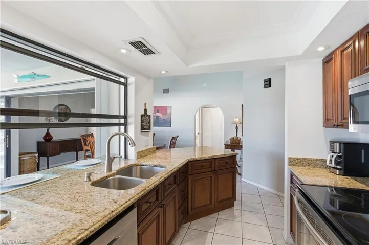 Kitchen with arched walkways, light stone countertops, recessed lighting, light tile patterned flooring, and appliances with stainless steel finishes