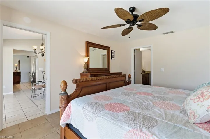 Bedroom featuring light tile patterned floors, a chandelier, ceiling fan, and freestanding refrigerator