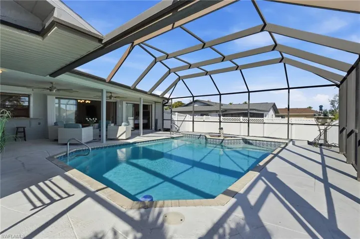 View of pool featuring a jacuzzi, an outdoor hangout area, glass enclosure, a patio area, and a sunroom
