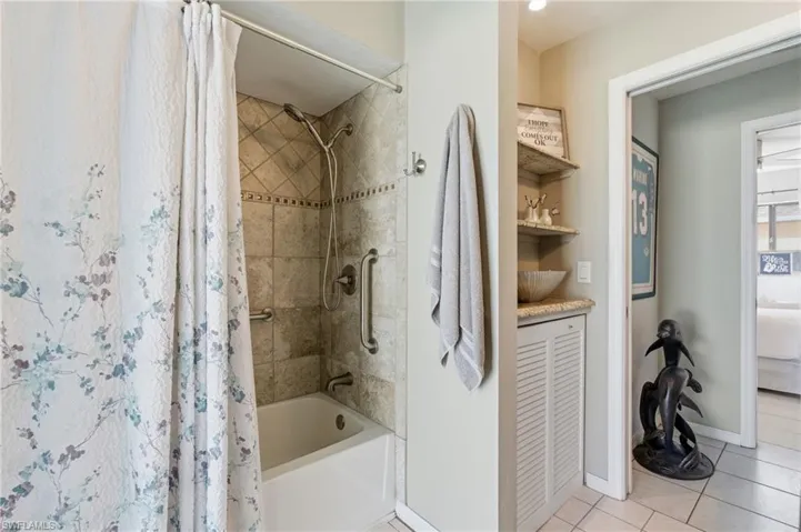 Full bathroom with shower / tub combo, light tile patterned floors, and ensuite bath