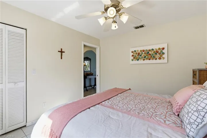 Tiled bedroom with ceiling fan and a closet