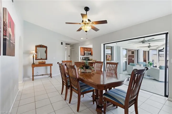 Dining room featuring a ceiling fan, light tile patterned floors, and arched walkways