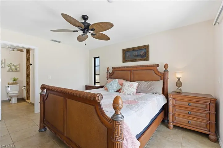 Bedroom featuring light tile patterned flooring, ceiling fan, and connected bathroom