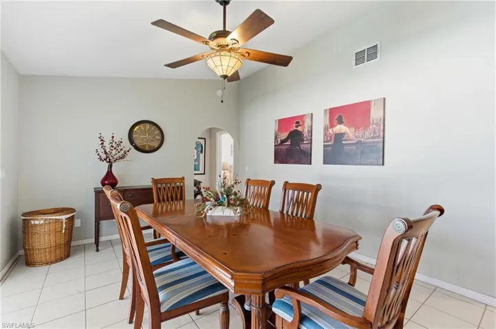 Dining room featuring arched walkways, light tile patterned flooring, and ceiling fan