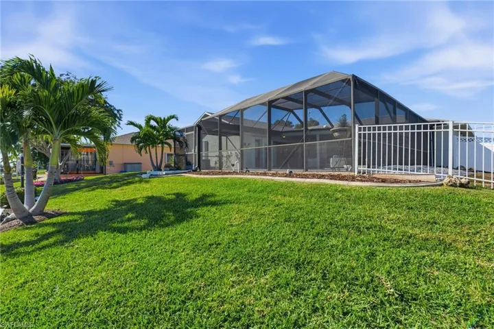 View of grassy yard featuring a sunroom and a lanai