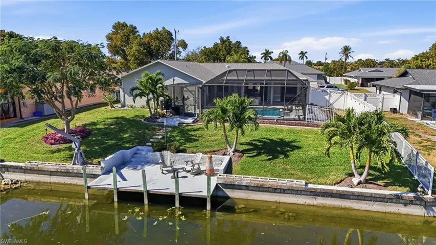 Rear view of property with a sunroom, glass enclosure, a fenced backyard, a water view, and a patio area