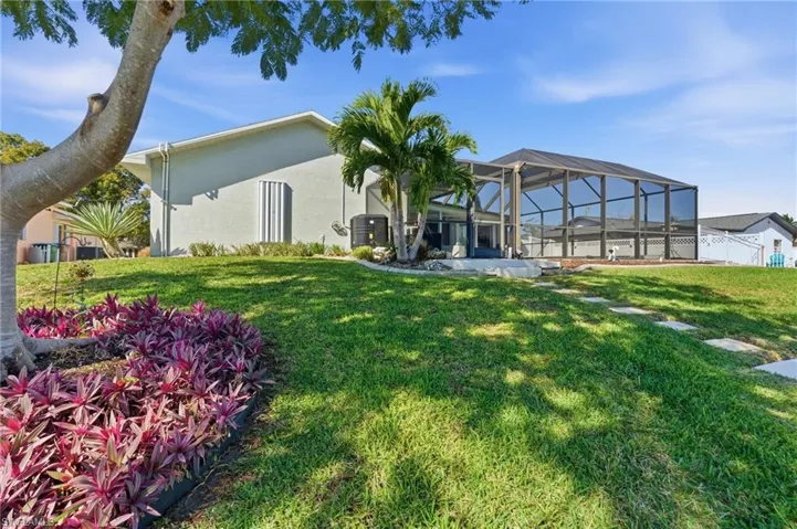 Rear view of house featuring glass enclosure, a sunroom, stucco siding, a yard, and a patio