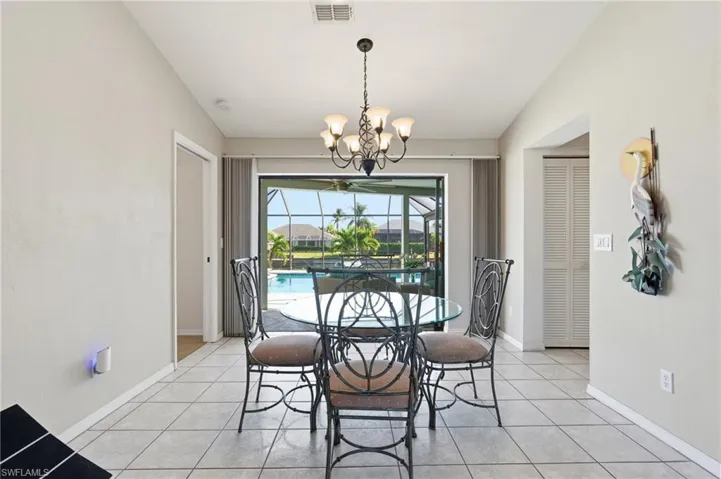 Dining room with light tile patterned floors, a chandelier, a sunroom, and lofted ceiling