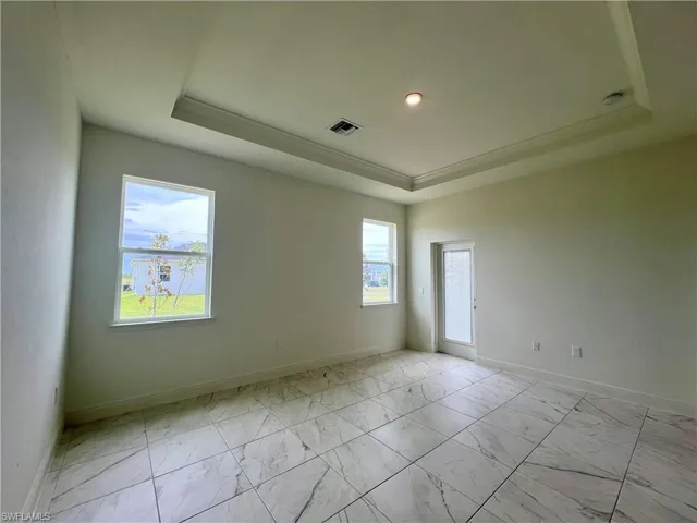 Spare room with a raised ceiling and light marble finish flooring