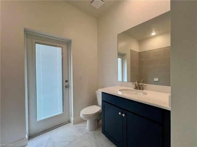 Half bathroom with vanity, light marble finish flooring, and a textured wall