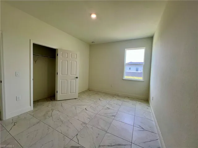 Unfurnished bedroom with light marble finish flooring and a walk in closet