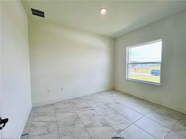 Spare room featuring light marble finish floors and baseboards