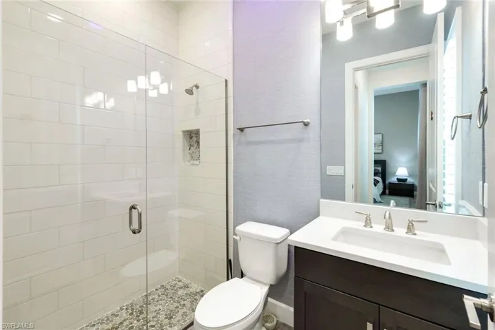Full bath featuring a shower stall, vanity, and a textured wall