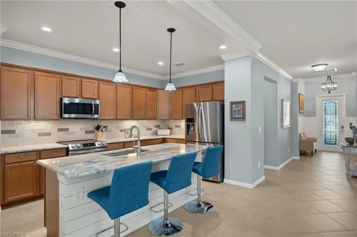 Kitchen featuring sink, an island with sink, stainless steel appliances, and ornamental molding