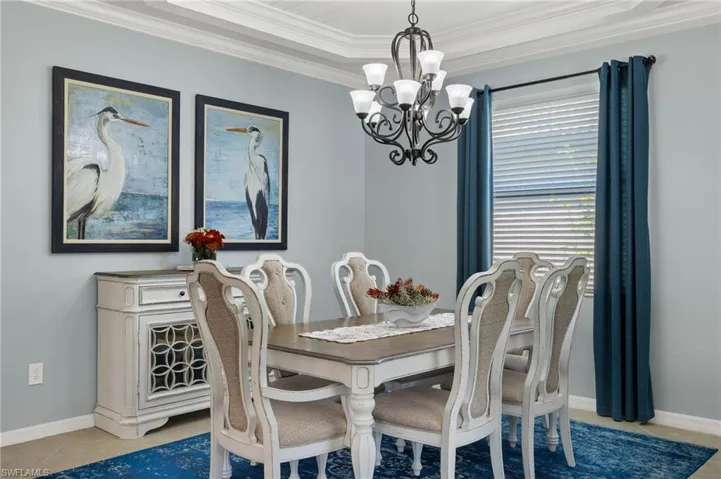 Tiled dining area with a tray ceiling, crown molding, and a chandelier
