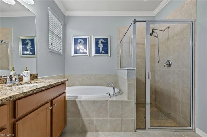 Bathroom with tile patterned floors, plus walk in shower, vanity, and ornamental molding