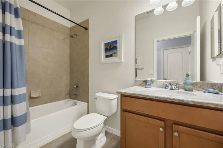 Full bathroom with tile patterned flooring, shower / bath combo, toilet, and vanity