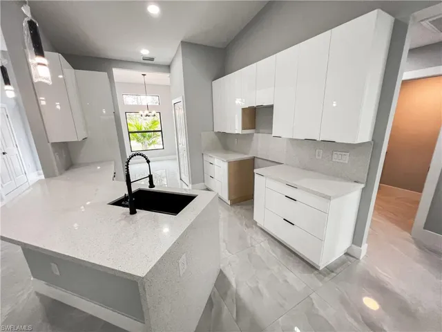 Kitchen with pendant lighting, a chandelier, sink, and white cabinetry