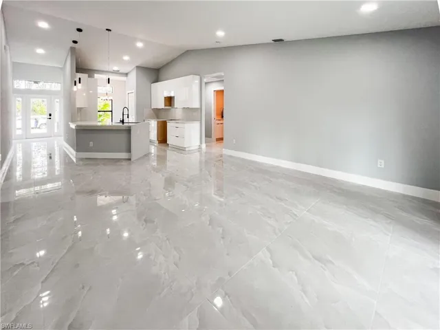 Unfurnished living room with french doors, lofted ceiling, and sink