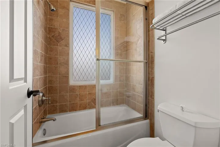 Bathroom featuring shower / bath combination with glass door and toilet