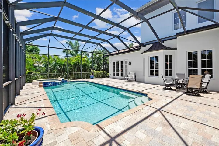 View of pool featuring screen enclosure, inground hot tub, and a patio