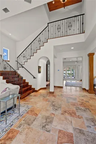 Foyer with a towering ceiling, tile flooring, ceiling fan and staircase with wrought iron railing