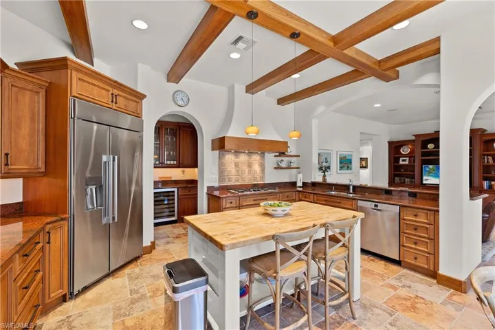 Kitchen featuring beverage cooler, beamed ceiling, appliances with stainless steel finishes, sink, and pendant lighting