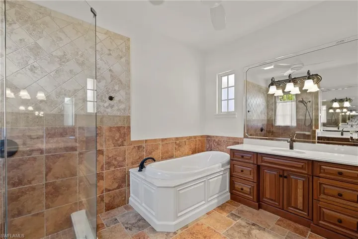 Bathroom featuring tile walls, tile floors, independent shower and bath, and vanities