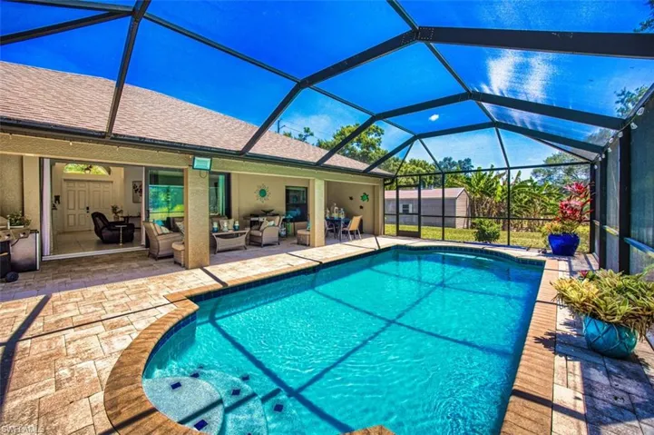 Outdoor pool with glass enclosure, an outdoor structure, an outdoor hangout area, a storage unit, and a patio