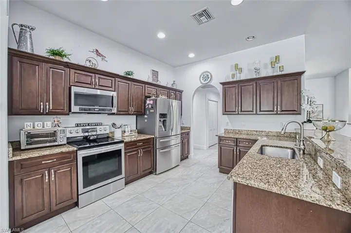 Kitchen with visible vents, a toaster, arched walkways, a sink, and stainless steel appliances