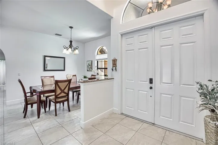Entrance foyer featuring arched walkways, baseboards, a notable chandelier, and light tile patterned flooring